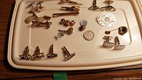 Overview of all cufflinks, tie clips, and pins arranged on a beige tray showing variety of designs and styles.