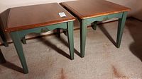 Two painted wood side tables with green painted legs and natural wood tops side by side on carpet