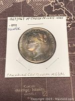 Obverse side of 1967 Canadian Centennial silver round showing Queen Victoria profile and date 1867, mounted in cardboard holder with handwritten notes.