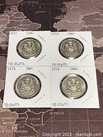 Four Canadian 50 cent coins dated 1971, 1972, 1973, and 1974 in cardboard holders.