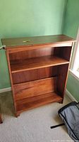 Front view of medium brown wooden bookcase showing two shelves and solid back panel.