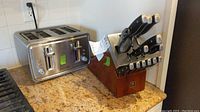 Photo showing the J A Henckels cutlery block with multiple knives alongside the Black & Decker 4-slice toaster on countertop.