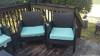 Set of 3 brown woven resin patio chairs with light blue seat cushions on a wooden deck. Chairs have armrests and show typical outdoor wear and scratches.