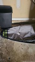 Gray padded Rhino Short surfboard bag on garage floor, showing shape and partial zipper