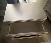 Top angle view showing the open top drawer and smooth silver finish with minor wear spots.