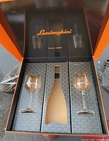 Opened branded Lamborghini gift box containing two crystal wine glasses and empty bottle slot
