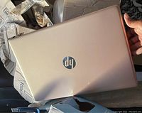 Closed view of the HP laptop lid showing rose gold color and dent damage on the top cover.