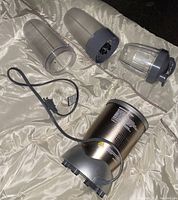 All NutriBullet components arranged showing cups, lids, extractor blades, power base and cord