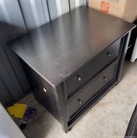 Lateral file cabinet angled view showing two drawers and top surface with minor wear marks.