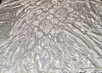 Top view of king size comforter showing cream fabric with gold paisley pattern and some wrinkles.