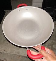 Top-down view of the 14.25-inch red Rachael Ray wok showing its silver nonstick interior with some light scratches. Two sturdy red silicone handles attached with rivets are visible.