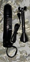 Black motor body of the hand blender with power cord coiled beside it on a patterned surface.