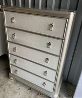 Full front view of silver five-drawer chest on turned legs