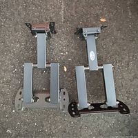 Pair of gray metal swivel TV wall mounts shown on asphalt ground from top view