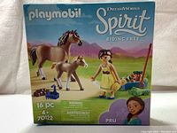 Front view of the Playmobil Spirit Riding Free boxed set showing the horse, foal, female figure, and accessories.