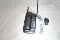 Panasonic 900 MHz cordless phone handset in base station with antenna, power adapter, and cords on white background.