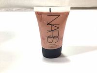 Front view of NARS Illuminator tube showing brand name, shade 'Orgasm', and product type.