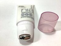 White tube of StriVectin NIA 114 Tech Neck Line Smoother serum with silver roller applicator and pink cap removed, showing product details and design