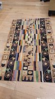 Full view of the Newman hand tufted wool area rug laid flat on a wooden floor showing all pattern and color details.