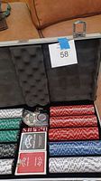 Open aluminum locking poker chip case with foam padding, showing poker chips, decks of cards, dice, and dealer button.