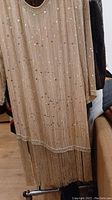 Front view of beige sequin and bead heavy flapper dress with fringe bottom and pearl bead collar and cuffs.