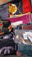 All eight scarves folded in box showing multiple patterns and materials