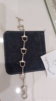 Full view of the linked stirrup sterling silver bracelet placed on a black pouch, toggle clasp visible