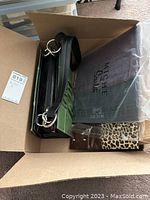 Box of various clutches including one in packaging and some in different fabrics and colors