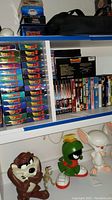 Shelf with multiple Dragon Ball Z VHS tapes and DVDs, three character figurines below them