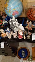 Photo showing a display of various Krystonian fantasy figurines, including a large seated king figure, turtle figure, and smaller characters near a globe and basketball display case