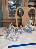 Four figurines grouped on table with china cabinet background