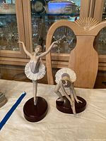 Front view of both figurines on table with cabinet background