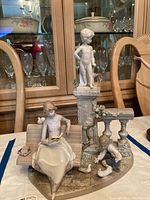 Front view of entire figurine showing woman on bench, child, doves and column pedestal