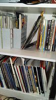 Shelf view of assorted magazines and books arranged upright and stored in plastic holders and loose on shelf
