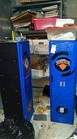 Two blue plastic New York Knicks sport lockers from front and angled side, showing Knicks logos, number 21 and NBA logos, located in basement with surrounding clutter
