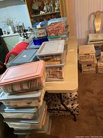 Stacked plastic storage bins on folding table containing sewing notions and materials