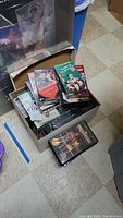 Box containing a mix of VHS tapes, some stacked loosely, others in the box, including Hometown Valentine's Special VHS tape visible on top.