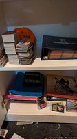 Overview of top and bottom shelves showing loose card stacks, baseball album, Nathan's hat, deck box, binders