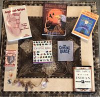 Books and crystal necklaces arranged on a patterned textile with titles visible, showing animal and crystal themes.