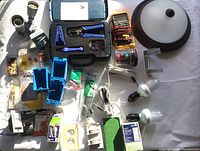 Photo showing assortment of electrical components including light fixtures, a yellow Fluke multimeter, a Datashark tool kit with blue tools, wiring, and outlet boxes.