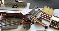 Wide view of router table, plunge router, bit cases, fence rails and insert plate laid out
