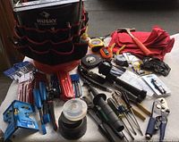 Overview photo showing the orange bucket with Husky tool liner filled with various hand tools including screwdrivers, files, clamps, a tripod work light, and measuring devices.