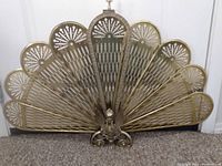 Full front view of the brass fireguard showing its fan shape and details.