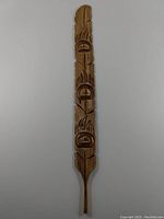 Full view of the carved feather showing its shape and detailed carving along its length.