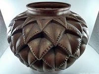 Front angle of large brown ceramic pot with raised diamond pattern and beaded edges on the surface