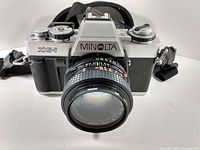 Front view of Minolta XG-1 camera with attached 50mm lens showing branding and lens details.