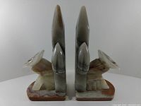 Side view of the pair of onyx stone bookends shown upright, highlighting their polished stone surfaces and geometric design features.