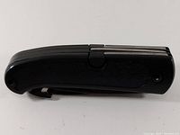 Closed view of pocket multi-tool showing textured black handle and folded blades.