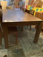 Three-quarter view of full table on area rug with surrounding chairs