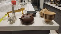 Overhead shot showing both teapots, sand-colored cups, black cups, dragon cutter, stand, and white figurine